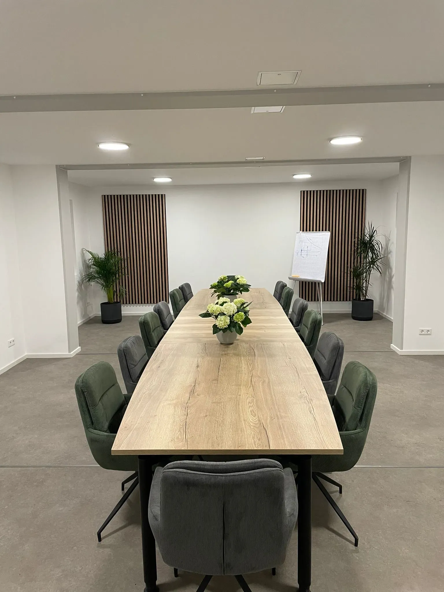 Schulungsraum von T&O Service mit langem Konferenztisch, Polsterstühlen, Flipchart und Blumenstrauß